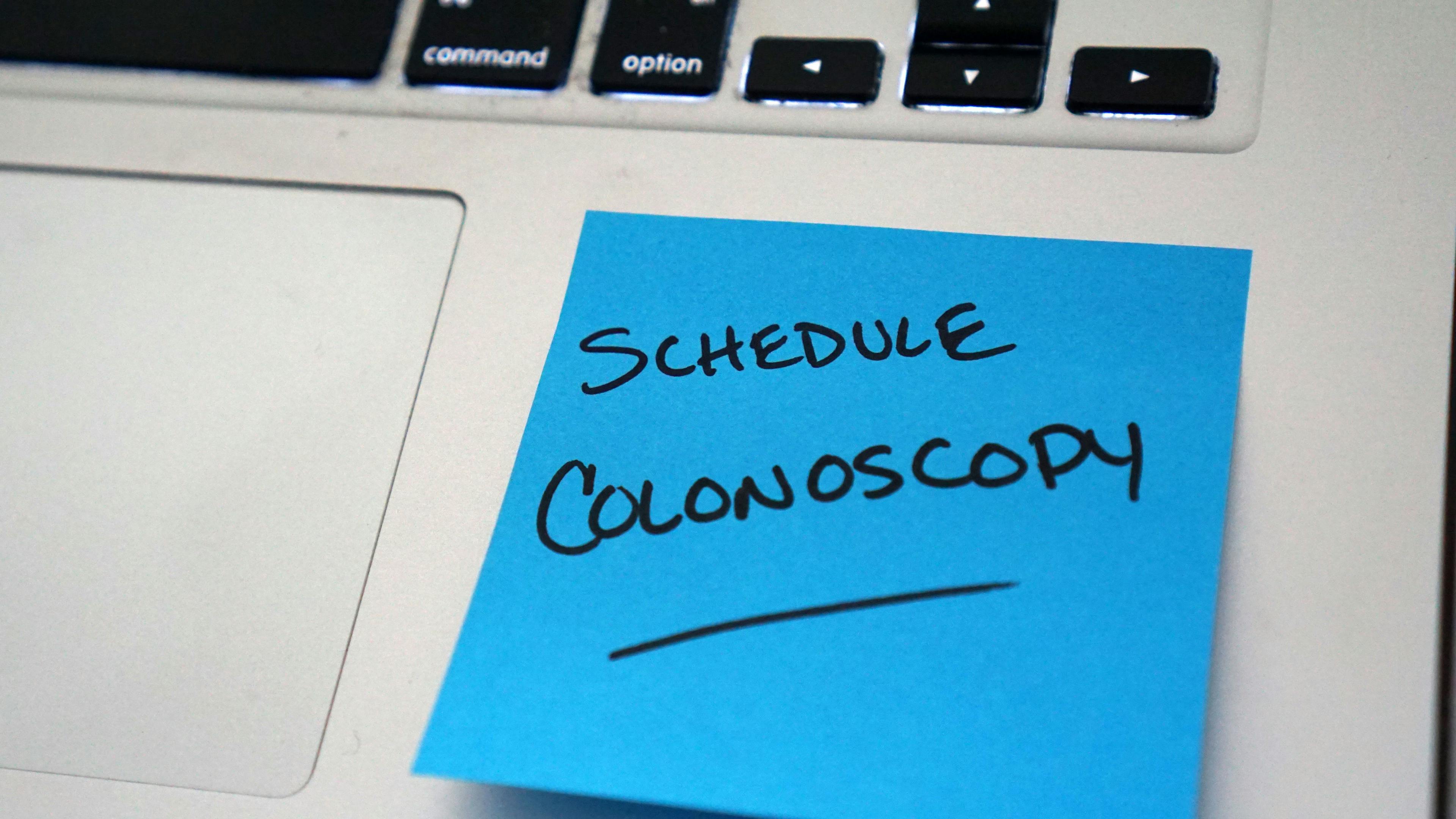 A blue sticky note reminding someone to schedule their colonoscopy