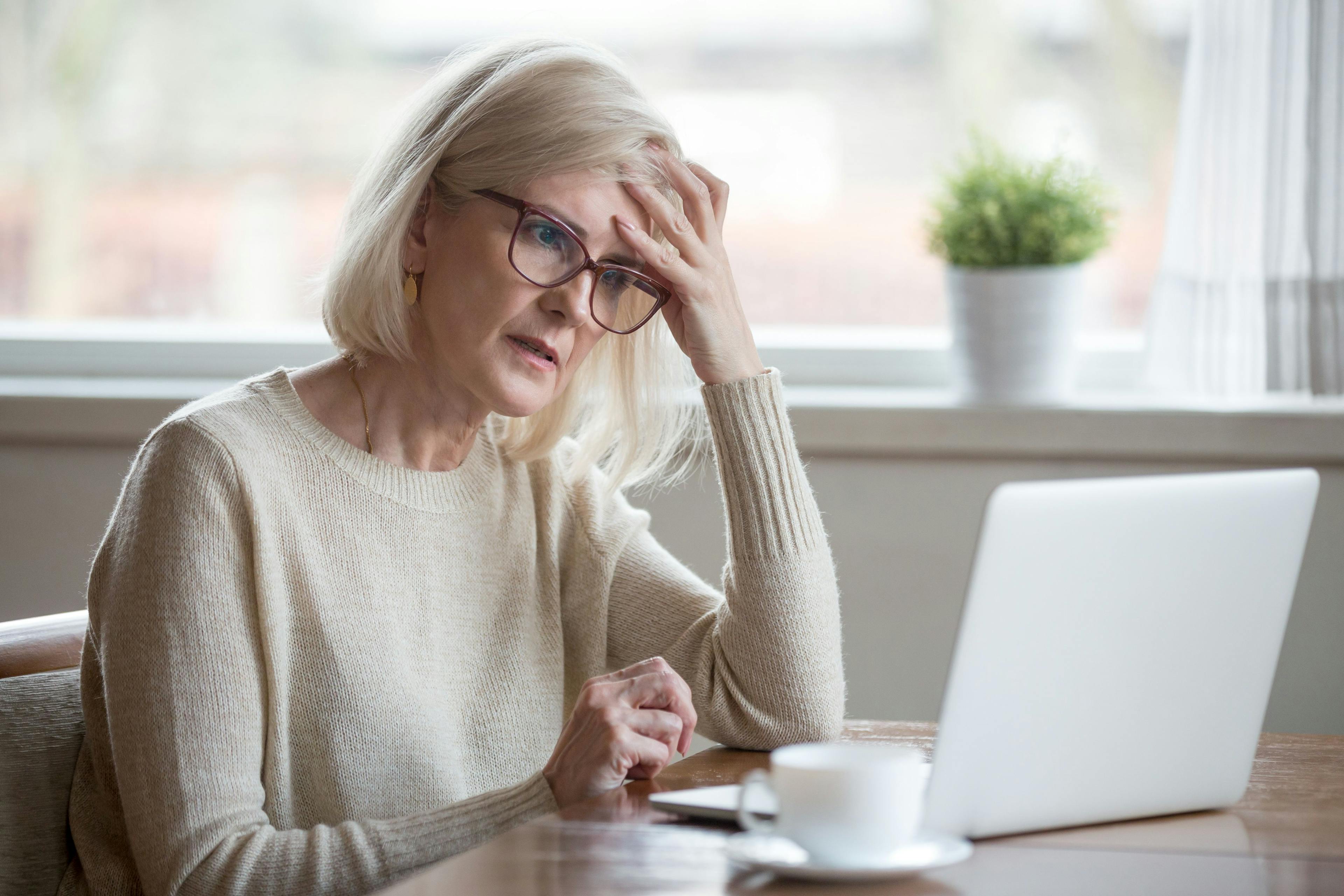 An older woman stares at her laptop, totally confused. 