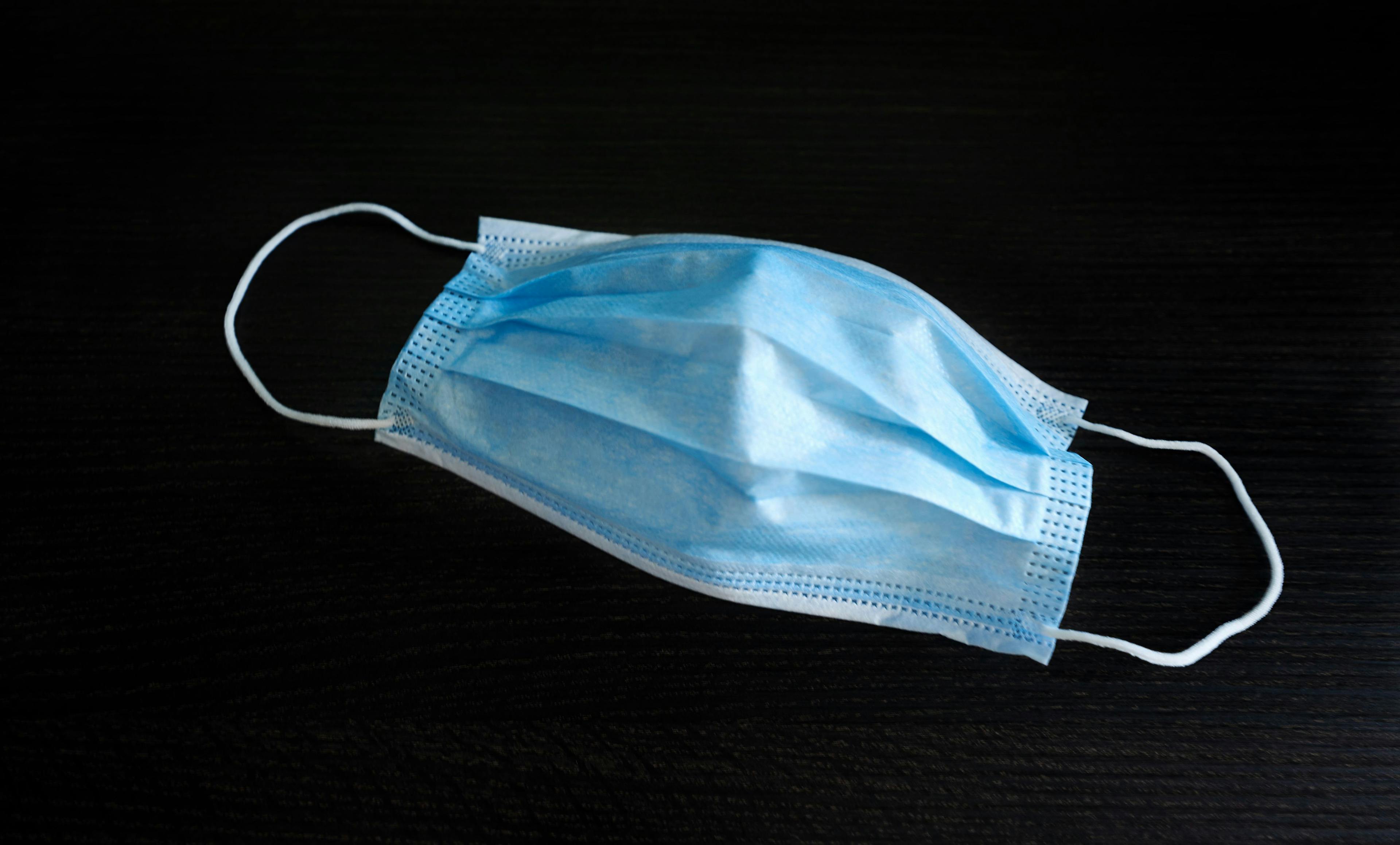 A blue surgical mask on a black background