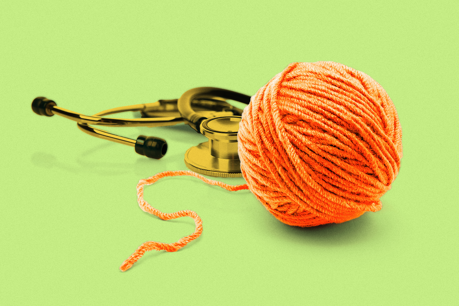 A stethoscope next to an unravelling ball of yarn on a light green background