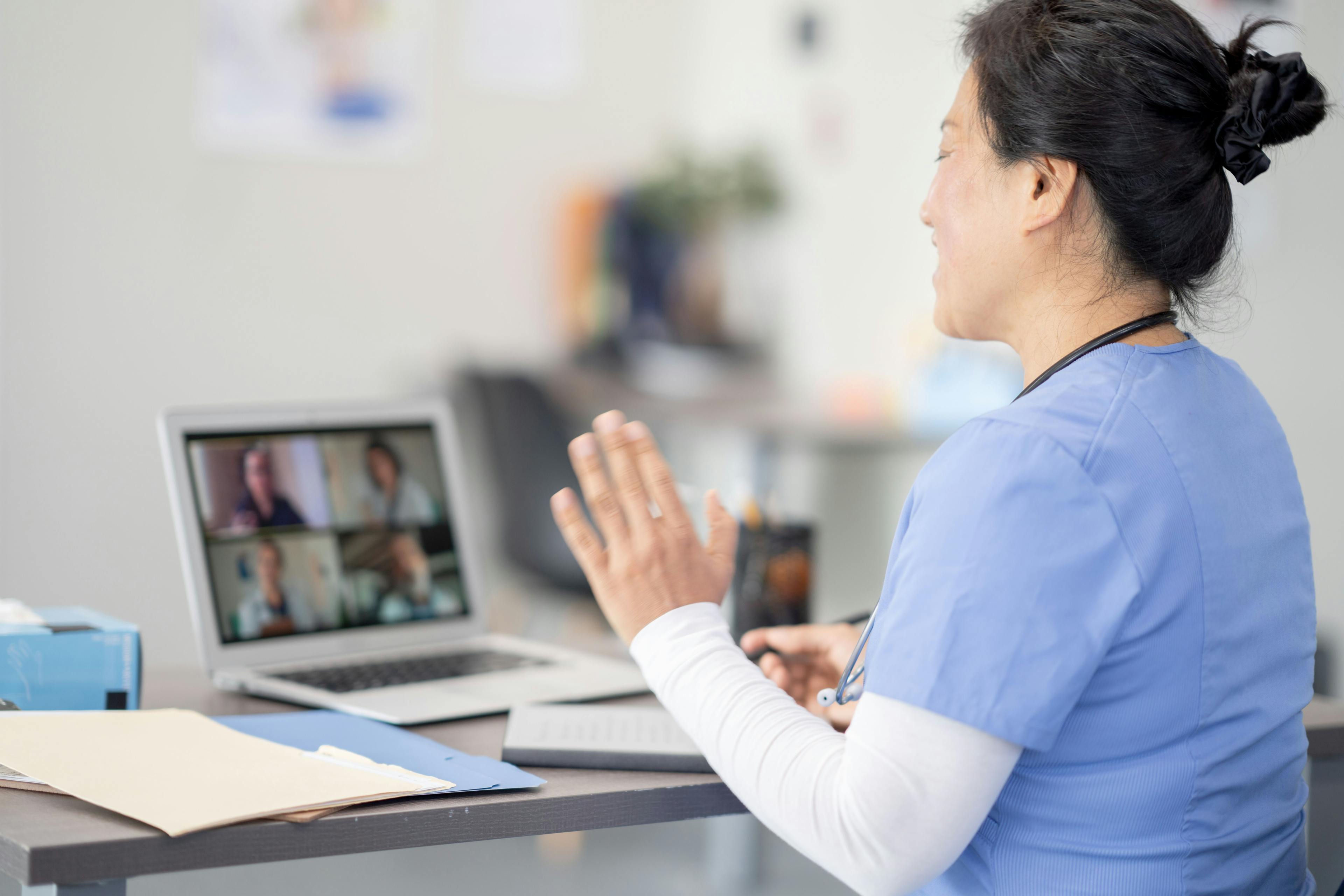 A medical professional video conferences with others on her laptop.