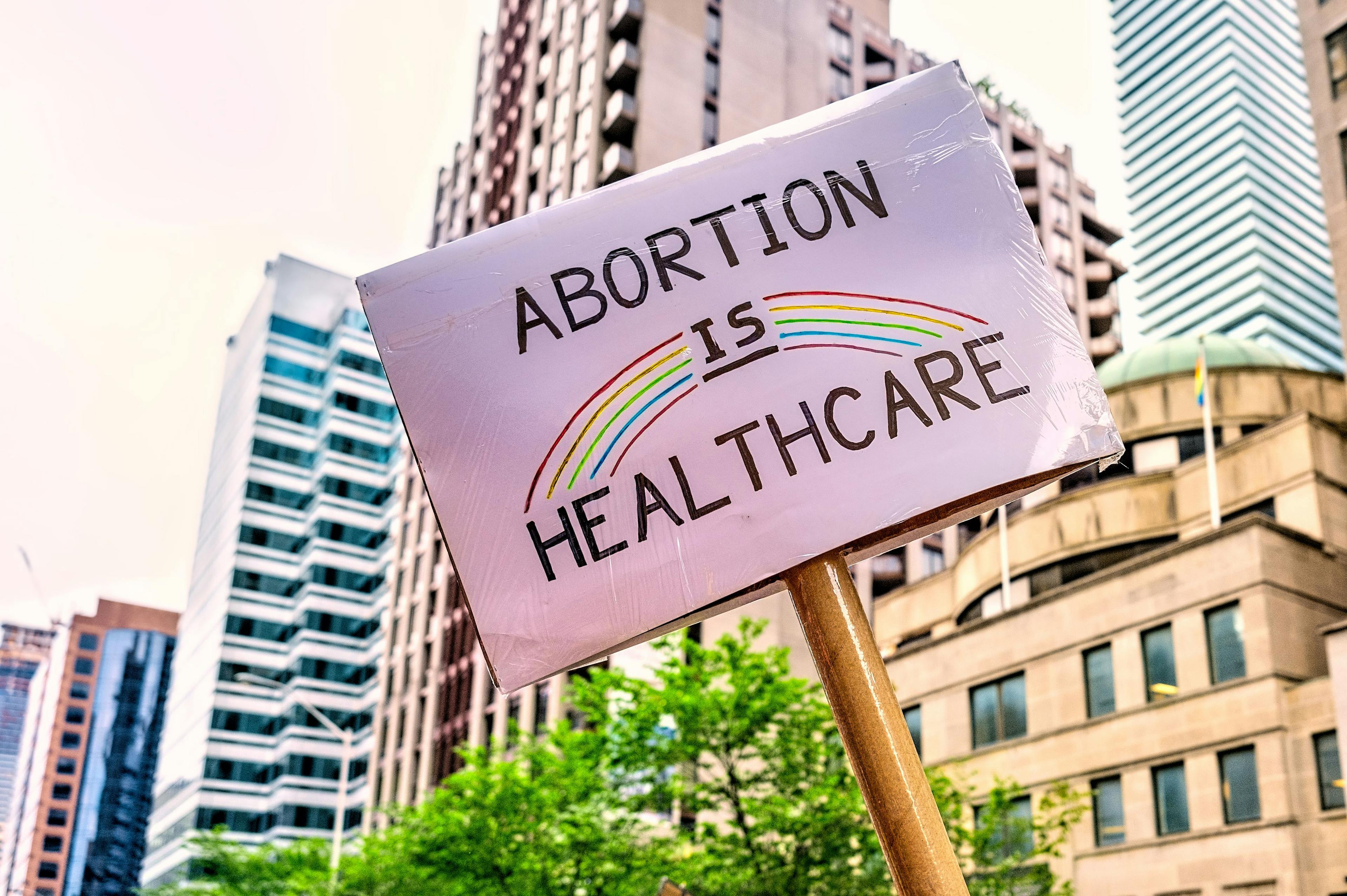 A handmade sign reading "Abortion is healthcare" with a rainbow on it.